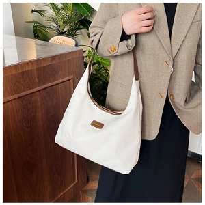 Detail of white corduroy hobo bag with contrast brown leather trim and retro texture