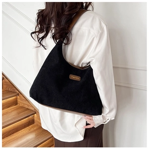 Detailed back view of a black corduroy tote bag with brown leather trim on stairs