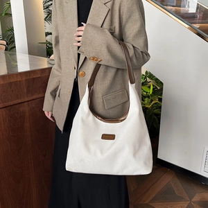White corduroy hobo tote bag with brown leather handles and vintage patch detail
