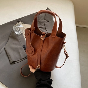 Borsa a secchiello in pelle caramello con manico superiore, tracolla e ciondolo smile