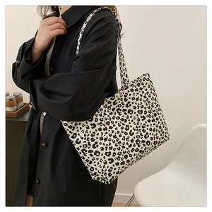 Side view of model wearing a large leopard print tote bag with thick shoulder straps