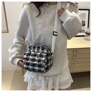 Detailed view of checkered crossbody bag with heart prints worn by a model in casual setting