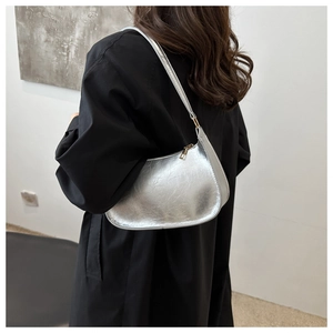 Sac hobo argenté métallisé avec texture plissée et fermeture éclair porté à l'épaule
