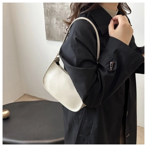 Sac sous le bras beige minimaliste en similicuir brillant porté par un mannequin élégant