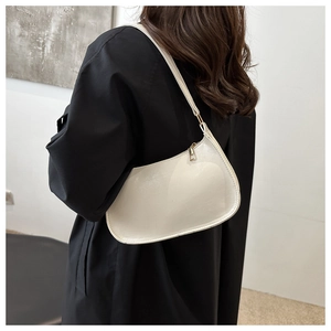 Vue latérale du sac croissant blanc crème au fini brillant porté par un mannequin
