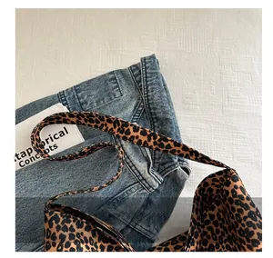 Détail de la poignée renforcée du sac cabas léopard sur un fond en jean décontracté