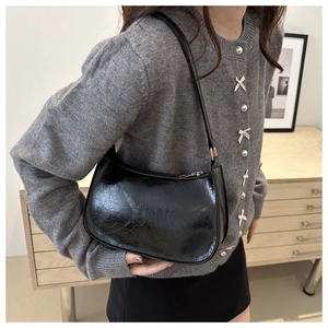 Détail du sac à bandoulière noir brillant en cuir craquelé avec fermeture éclair dorée