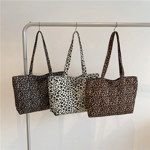 Three leopard print canvas tote bags in various patterns hanging on a rack