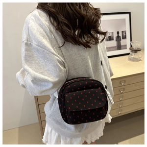 Détail du sac bandoulière noir à cœurs rouges et bandoulière tissée blanche en ambiance