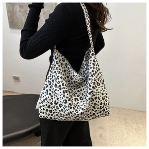 Vue détaillée du grand sac cabas à imprimé léopard porté à l'épaule sur un pull noir