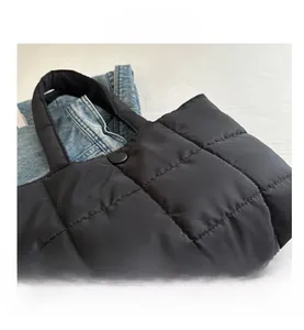 Detail of black quilted puffer tote bag featuring square stitching and round button closure