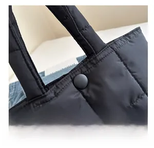 Detailed macro view of the black quilted nylon tote bag with a matte snap button closure