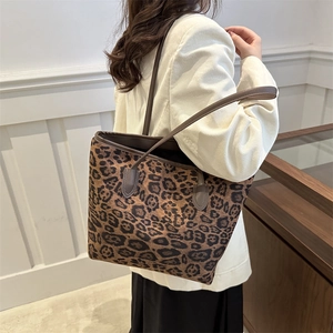 Borsa tote leopardata vintage con manici in pelle marrone indossata a spalla da donna