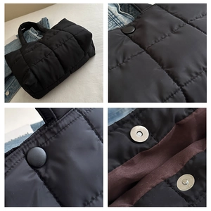 Detail of metal magnetic closure and deep brown lining on a black quilted tote bag