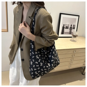 Vue détaillée du sac cabas en toile noire avec imprimé nœuds blancs et bandoulière