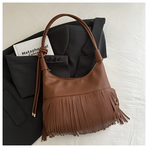 Close-up of caramel brown leather shoulder bag with long fringes and knotted handle detail