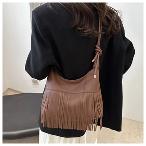 Detail of brown leather hobo bag featuring elegant fringe and knotted shoulder strap