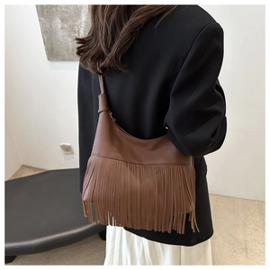 Primer plano de bolso de cuero marrón caramelo con flecos largos y forma de luna