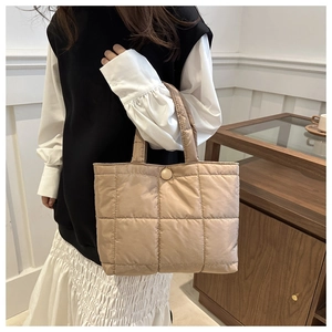 Detail of beige quilted puffer tote bag with square stitching and soft padded handle