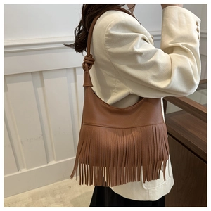 Close-up of caramel brown shoulder bag with tassel details and pebbled leather texture
