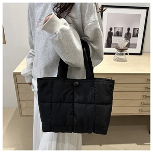 Quilted tote bag in black nylon with square stitching pattern shown on a shoulder