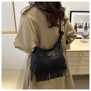 Detalle de bolso hobo negro con flecos largos de cuero y herrajes dorados elegantes