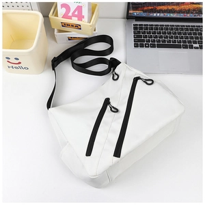 Detail of white nylon crossbody tote bag showing black diagonal zippers and adjustable strap