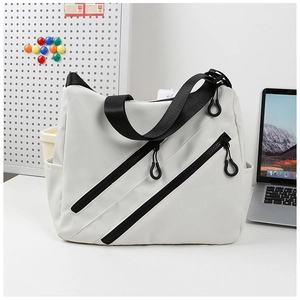 Detail showing dual black zippers and pocket texture on large white nylon tote bag