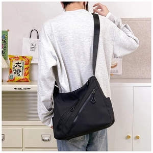 Black high-capacity nylon messenger bag with dual diagonal zipper pockets shown on model