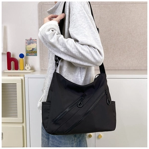 Detail of black nylon shoulder bag with dual zipper pockets and adjustable strap