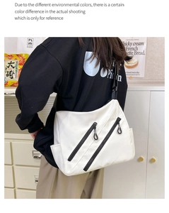 White large capacity crossbody bag with multiple black zipper pockets shown on model