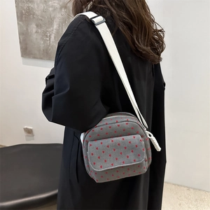 Chic grey canvas crossbody bag with red heart pattern and wide white shoulder strap
