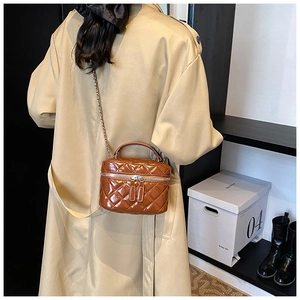 Detail of a brown quilted leather crossbody bag with chain strap and handle shown on model