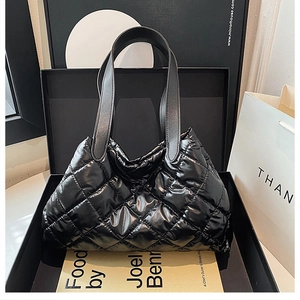Detail of black quilted puffer bag with large rhombus stitching and glossy finish