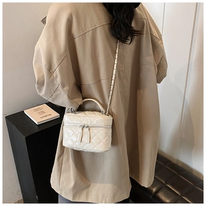Chic beige quilted mini bag with glossy finish and metal chain strap on model