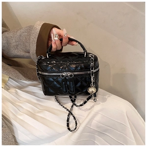 Detail of black quilted leather vanity case featuring chain strap and gold-tone zippers
