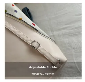 Détail de la boucle en métal réglable sur un sac hobo beige avec doublure à pois