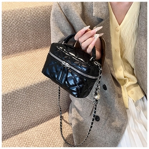 Detail of black quilted leather mini box bag with silver zipper and chain strap