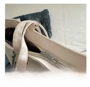 Détail de la fermeture éclair argentée et de la bandoulière sur le sac fourre-tout blanc