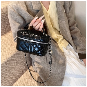 Detail of glossy quilted black vanity case bag with silver chain and leather handle