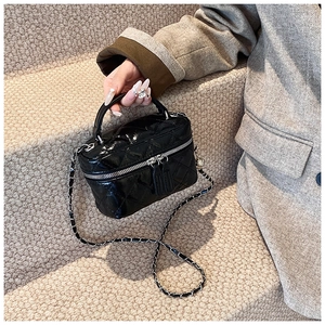 Detailed view of a quilted black leather mini box bag with gold chain and handle