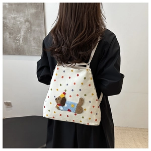 Détail d'un sac à dos en toile blanche avec pois colorés et broderie chiot en peluche