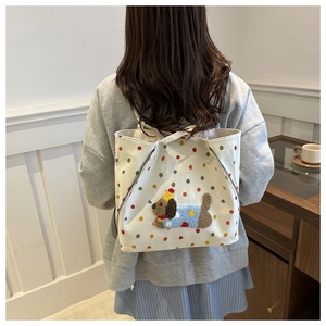 Gros plan d'un sac cabas en toile blanche avec pois colorés et broderie chien en peluche