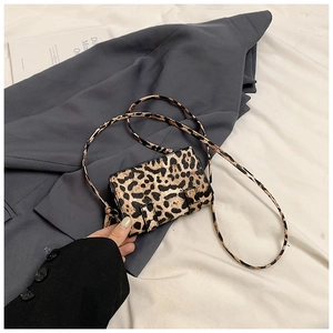 Detail of a leopard print mini square bag with dual buckle straps on a grey blazer