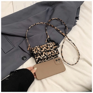 Detailed macro view of a mini leopard print crossbody bag compared to a smartphone