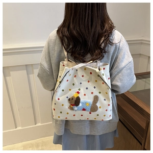 Détail du sac à dos en toile blanc cassé à pois colorés et broderie de chien mignon