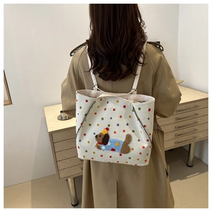 Détail d'un sac en toile blanc avec pois colorés et broderie de chiot en relief