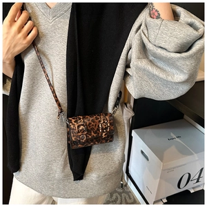 Close-up of leopard print mini crossbody bag with double buckle and thin shoulder strap