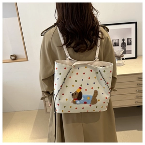 Vue portée d'un grand sac cabas en toile blanche à pois avec écusson chiot mignon