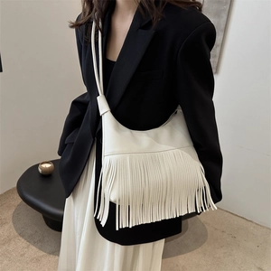 Bolso de hombro blanco de cuero con flecos llevado por modelo en un estudio moderno